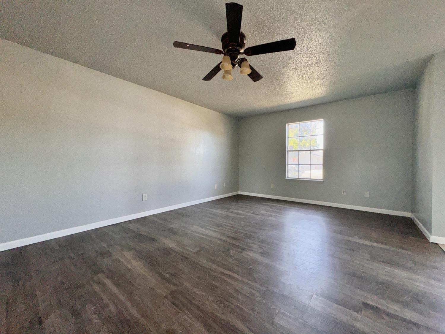 4707 48th Street Lubbock, TX 79414 - Photo 8 of 18 an empty room with wooden floor fan and windows