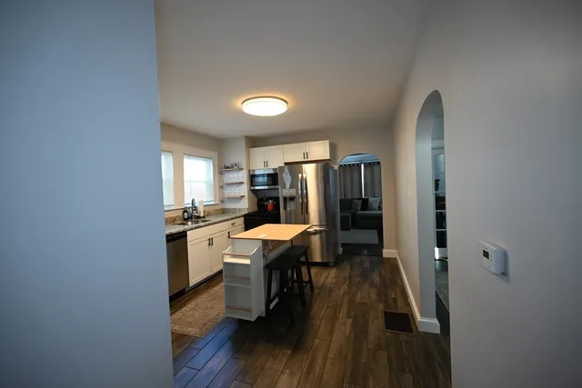 a kitchen with a refrigerator a sink dishwasher a dining table and chairs with wooden floor