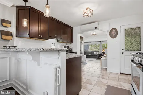 a kitchen with granite countertop a refrigerator a stove and white cabinets with wooden floor