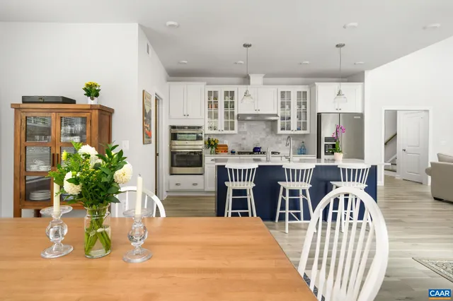 a dining room with furniture a potted plant and kitchen view