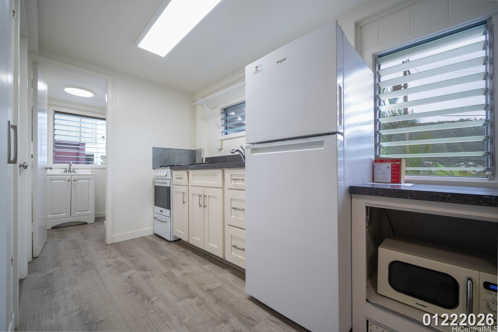 3033 Woolsey Place, Unit DOWNSTAIRS) Honolulu, HI 96822 - Photo 8 of 20 a kitchen with white cabinets and stainless steel appliances