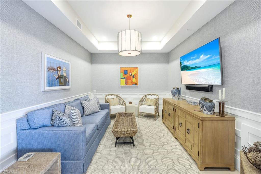1135 3rd Avenue South, Unit 319 Naples, FL 34102 - Photo 11 of 19 a living room with furniture a chandelier and a flat screen tv