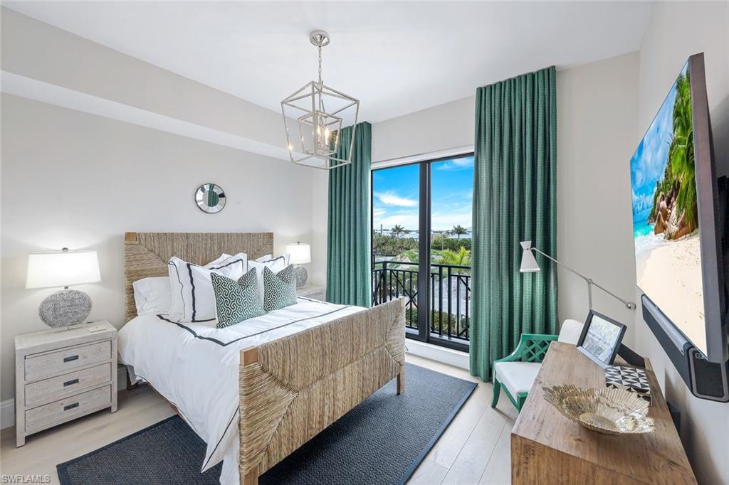 1135 3rd Avenue South, Unit 319 Naples, FL 34102 - Photo 9 of 19 a bedroom with a bed and a chandelier