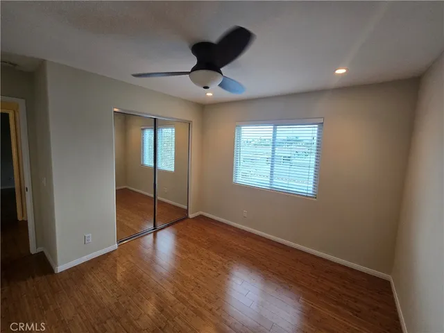 an empty room with wooden floor chandelier fan and windows