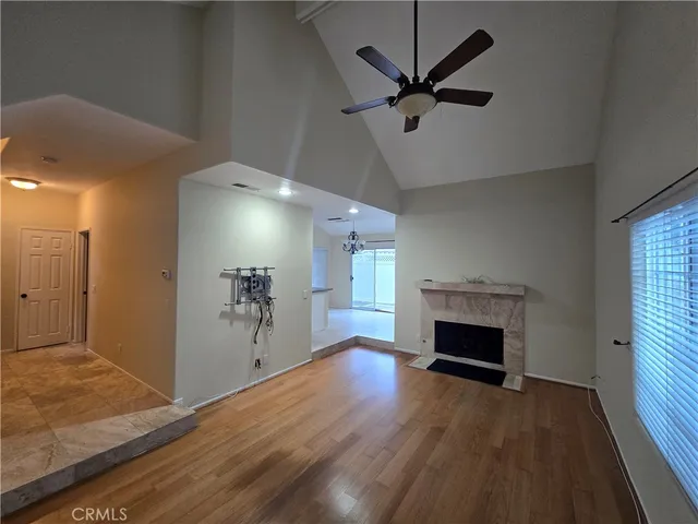 a view of a livingroom with a fireplace a ceiling fan and wooden floor