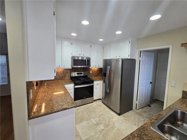 a kitchen with granite countertop a refrigerator and a stove top oven