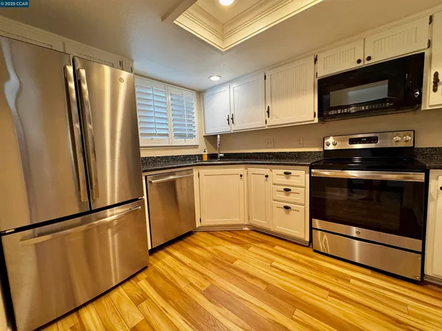 a kitchen with granite countertop a refrigerator stove and microwave
