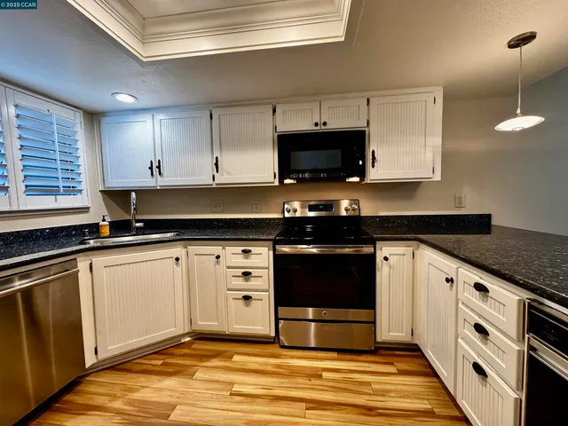 a kitchen with stainless steel appliances granite countertop a stove a sink and a microwave
