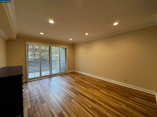 a view of an empty room with wooden floor and a window