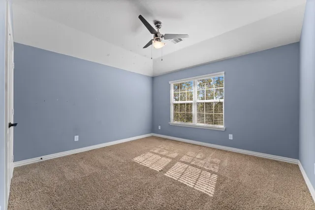 a view of a livingroom with a ceiling fan & windows