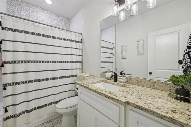 a bathroom with a granite countertop sink a toilet and mirror