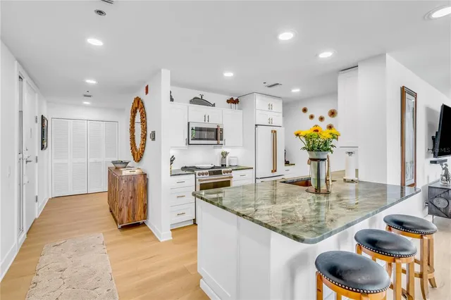 a kitchen with stainless steel appliances granite countertop sink stove refrigerator and cabinets