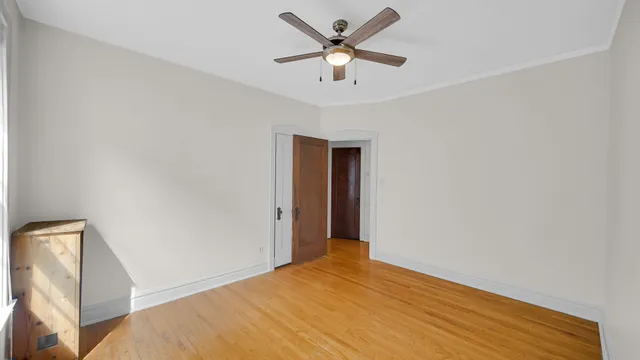 a view of a big room with wooden floor and a chandelier fan