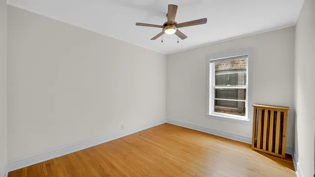 an empty room with a window and ceiling fan