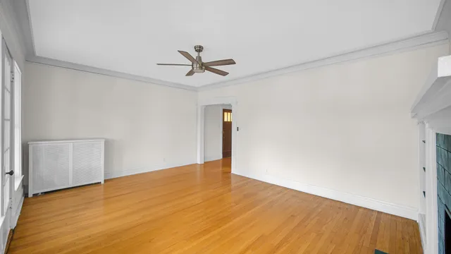 a view of empty room with wooden floor and ceiling fan