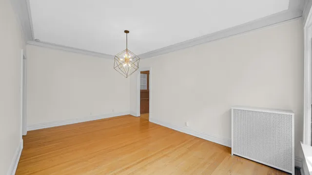 a big room with chandelier fan and wooden floor