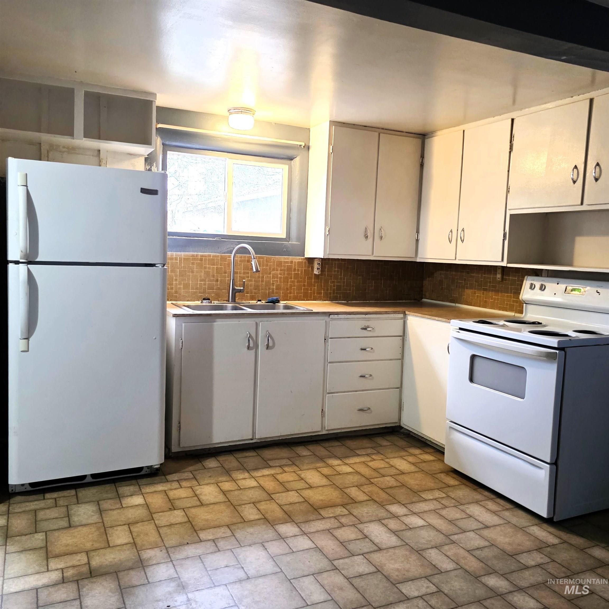 935 Preston Avenue Lewiston, ID 83501 - Photo 3 of 22 Kitchen featuring white appliances, white cabinets, brick patterned floors, and tasteful backsplash