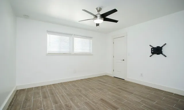 an empty room with a window and ceiling fan