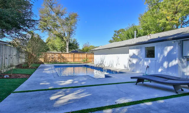 a view of backyard with swimming pool and wooden fence