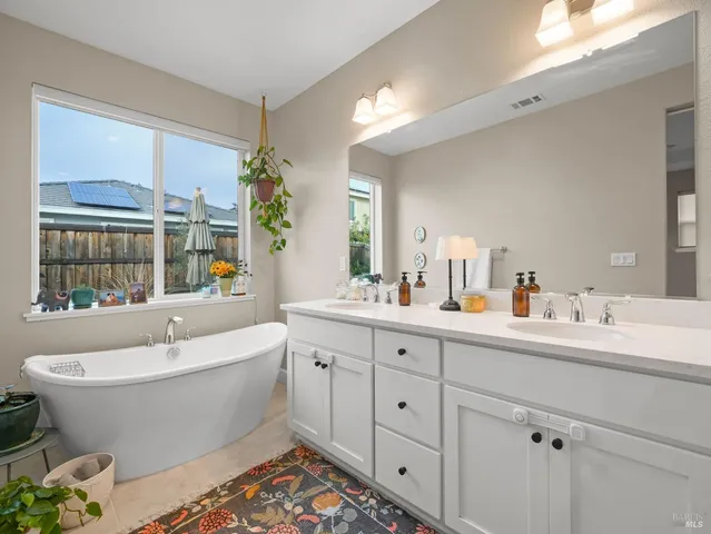 a bathroom with a white tub a sink and a window