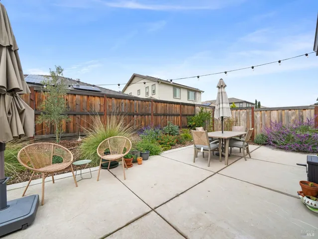 a view of a patio with table and chairs with plants and wooden fence
