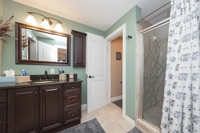 a bathroom with a granite countertop sink a mirror a vanity and a shower