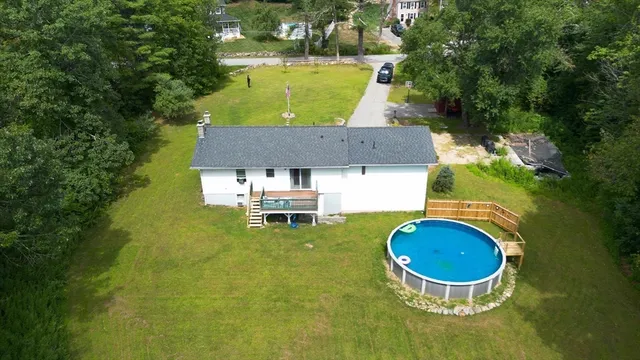 an aerial view of a house with swimming pool and trees