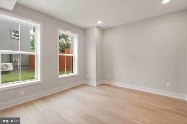 a view of an empty room with wooden floor and a bathroom