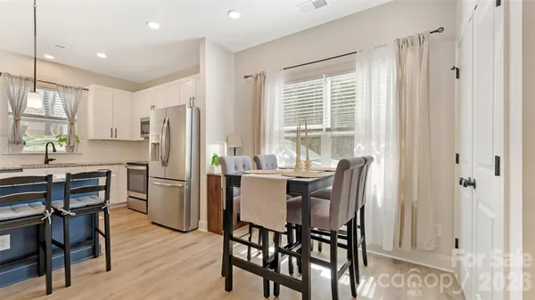 a kitchen with stainless steel appliances a dining table chairs refrigerator and sink