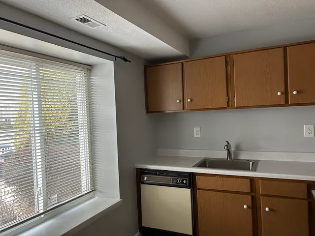 a kitchen with stainless steel appliances granite countertop white cabinets and a window