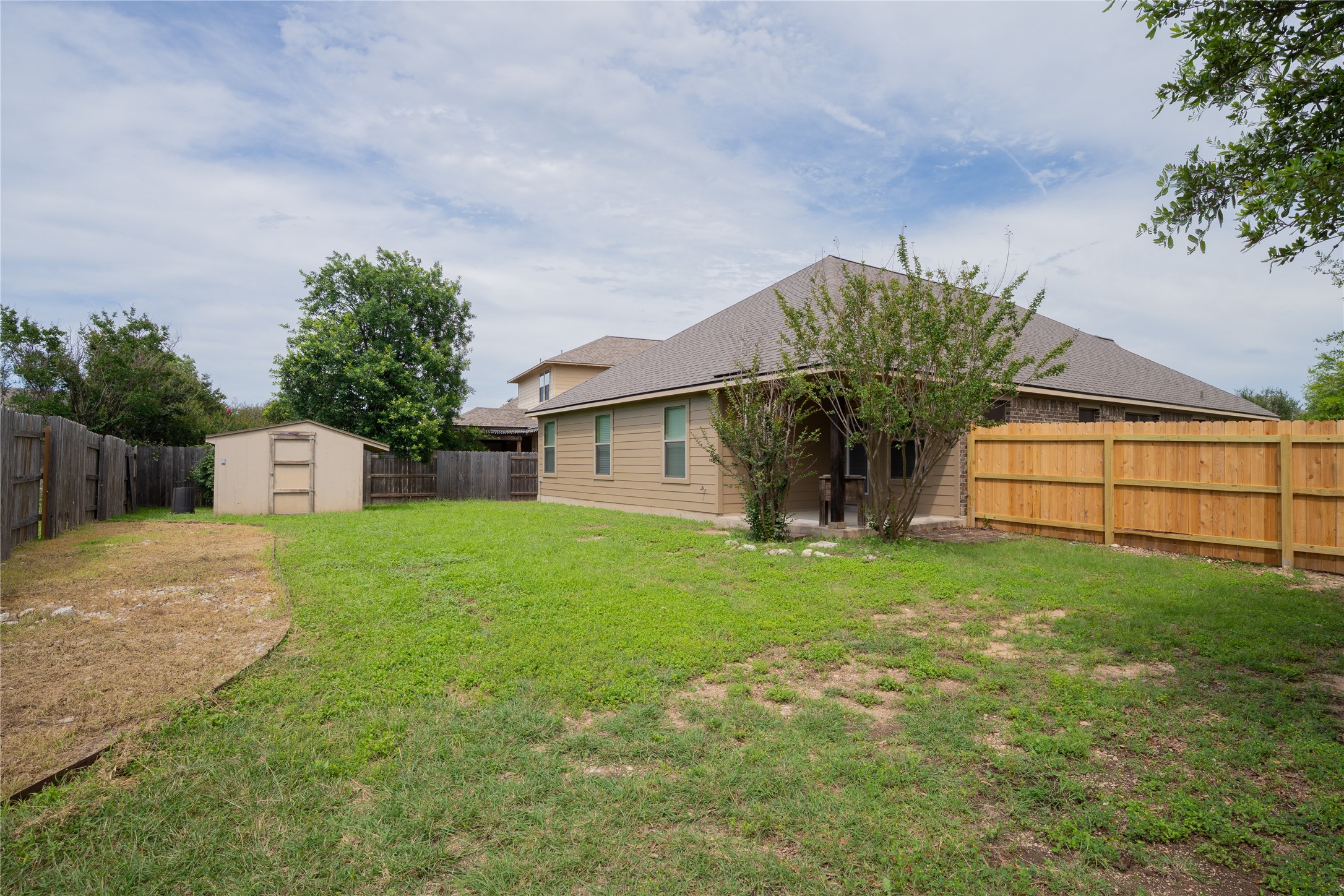 403 Tascate Street Georgetown, TX 78628 - Photo 24 of 26 A spacious yard boasts both new and established fencing, alongside a versatile storage shed.