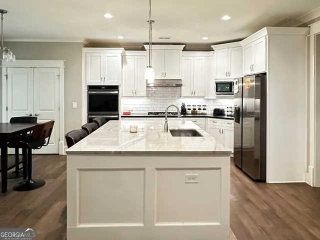 a kitchen with stainless steel appliances granite countertop a kitchen island a stove a refrigerator a sink and a island