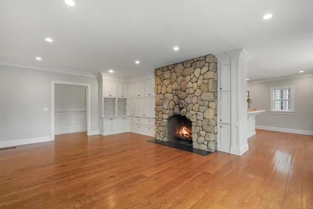 a view of an empty room with wooden floor fireplace and a window