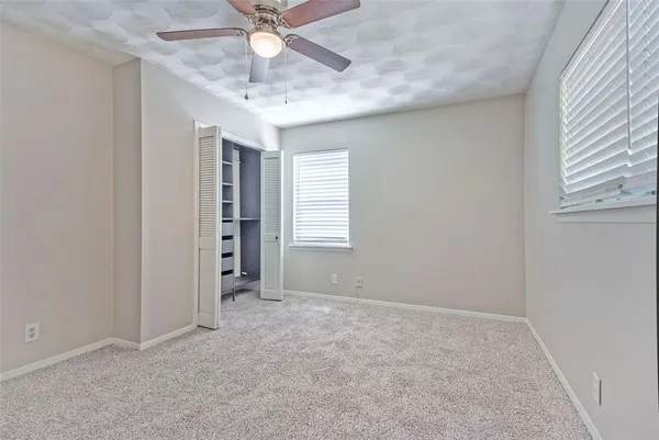an empty room with chandelier fan and windows