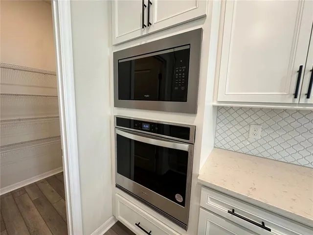 a view of a refrigerator in kitchen and an empty room with wooden floor