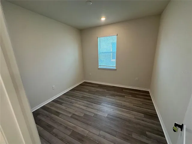 a view of an empty room with wooden floor and closet