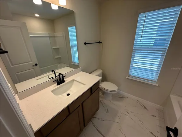 a bathroom with a sink a toilet a mirror a vanity and bathtub