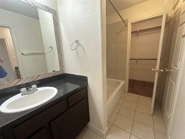 a bathroom with a granite countertop sink a mirror and shower