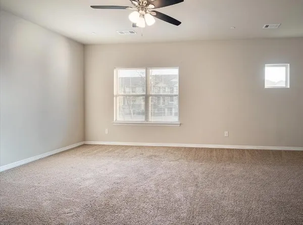 an empty room with windows and fan
