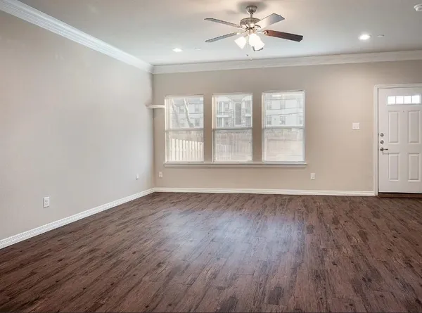 an empty room with wooden floor chandelier fan and windows