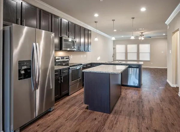 a kitchen with stainless steel appliances granite countertop a refrigerator a sink dishwasher a stove and a microwave oven on table with wooden floor