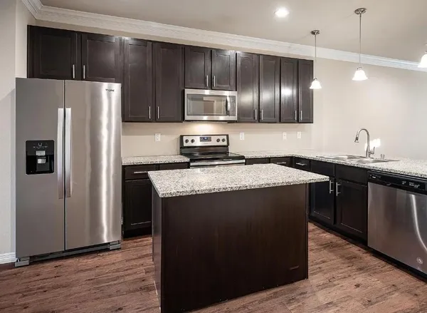 a kitchen with kitchen island granite countertop stainless steel appliances a refrigerator and a sink