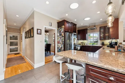 a kitchen with granite countertop stainless steel appliances a stove top oven and a refrigerator