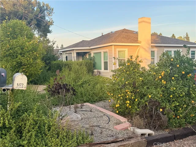 a front view of a house with a yard and trees