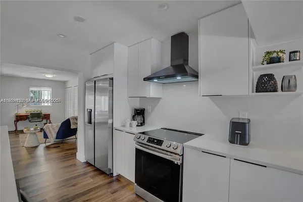 a kitchen with stainless steel appliances granite countertop a refrigerator a stove and a wooden floors