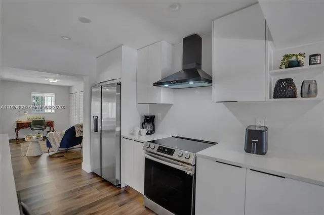 a kitchen with stainless steel appliances granite countertop a refrigerator a stove and a wooden floors