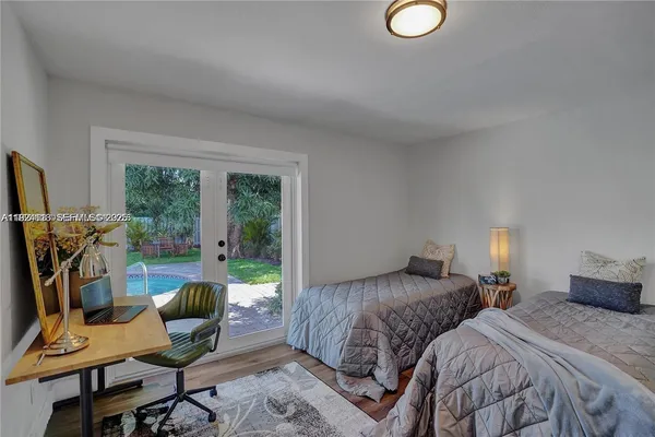 a bedroom with a bed a desk and chair with wooden floor