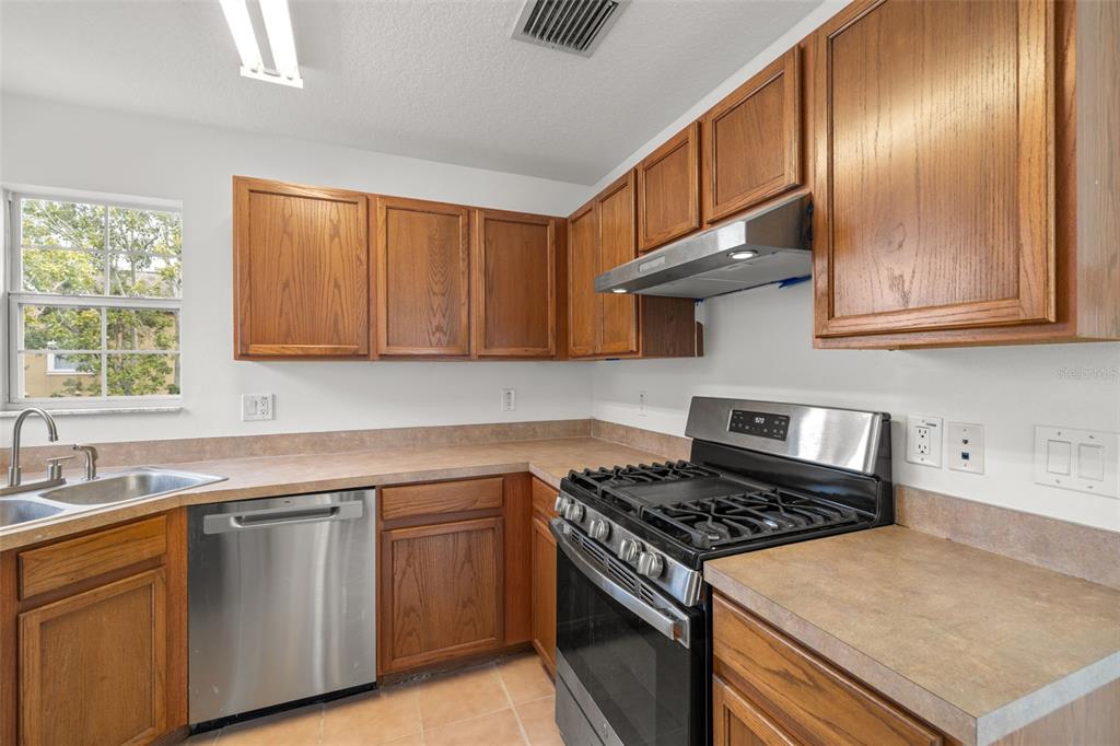5950 Beaconpark Street Lithia, FL 33547 - Photo 45 of 56 a kitchen with stainless steel appliances granite countertop a stove a sink dishwasher and microwave oven