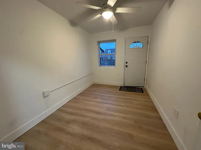 en empty room with wooden floor and ceiling fan