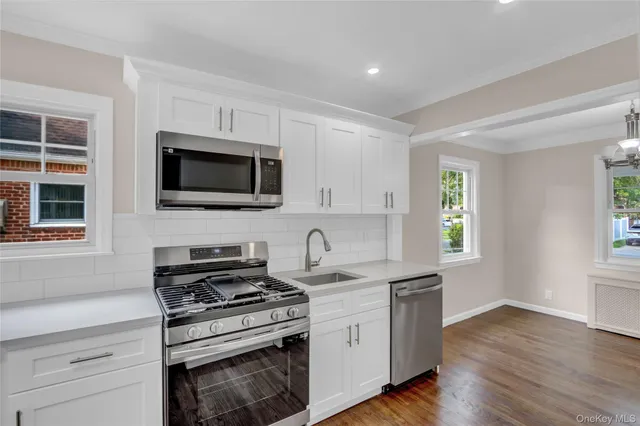 a kitchen with stainless steel appliances a stove a microwave a sink and cabinets